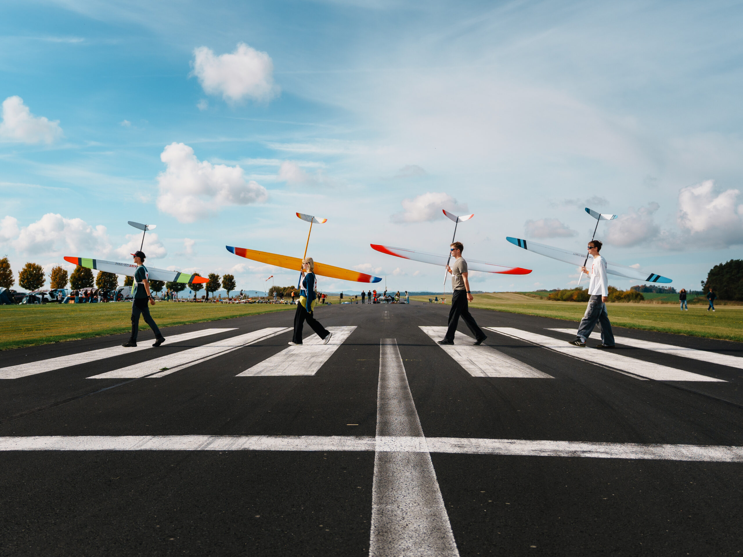 A group of four young pilots crossing the runway like the Beatles cross the street on the abbey road album cover