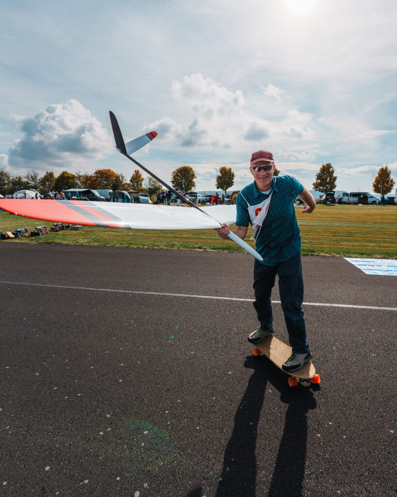 a competitor riding a skateboard while holding is f3b glider